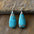 Natural stone copper teardrop earrings on rock background.