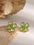 Stainless steel zircon lucky clover earrings in green with 18K gold-plated finish on natural stone background.