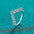 925 sterling silver V shape ring with moissanite stones on turquoise background.