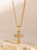 Stainless steel zircon cross pendant necklace with 18K gold plating displayed on a beige stone.