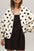 Heart print collared neck zip up jacket with pockets, worn over a black dress.