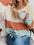 Color block round neck long sleeve sweater in pastel shades worn by a woman holding a coffee mug.