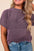 Corded knit mock neck short sleeve t-shirt in purple, ribbed texture, worn by a smiling woman.