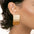 Stainless steel rectangle earring, 18K gold-plated, worn on ear.