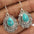 Artificial turquoise alloy teardrop dangle earrings with intricate detailing.