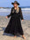 Plus size black embroidered tie neck long sleeve dress on beach.