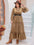 Plus size frill tie neck long sleeve dress in brown worn by a person, featuring a belted waist and tiered design.