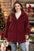 Plus size burgundy zip-up long sleeve hooded outerwear with pockets in a festive setting.