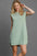 Umgee Round Neck Sleeveless High-Low Curved Hemline Mini Dress in green.